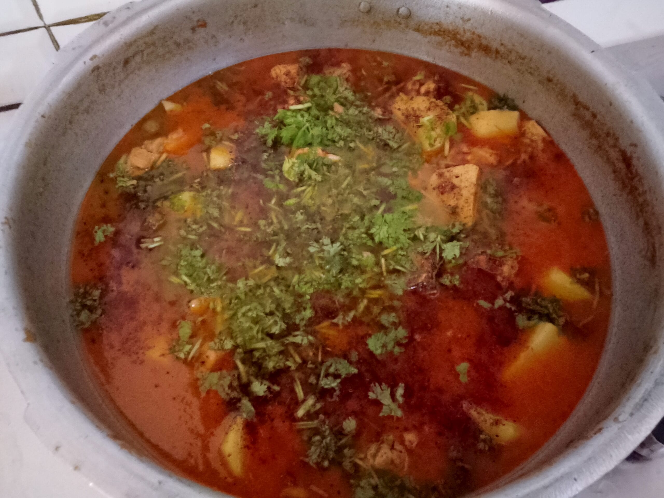 Final serving of delicious Aloo Chicken Recipe garnished with fresh coriander and green chilies.
