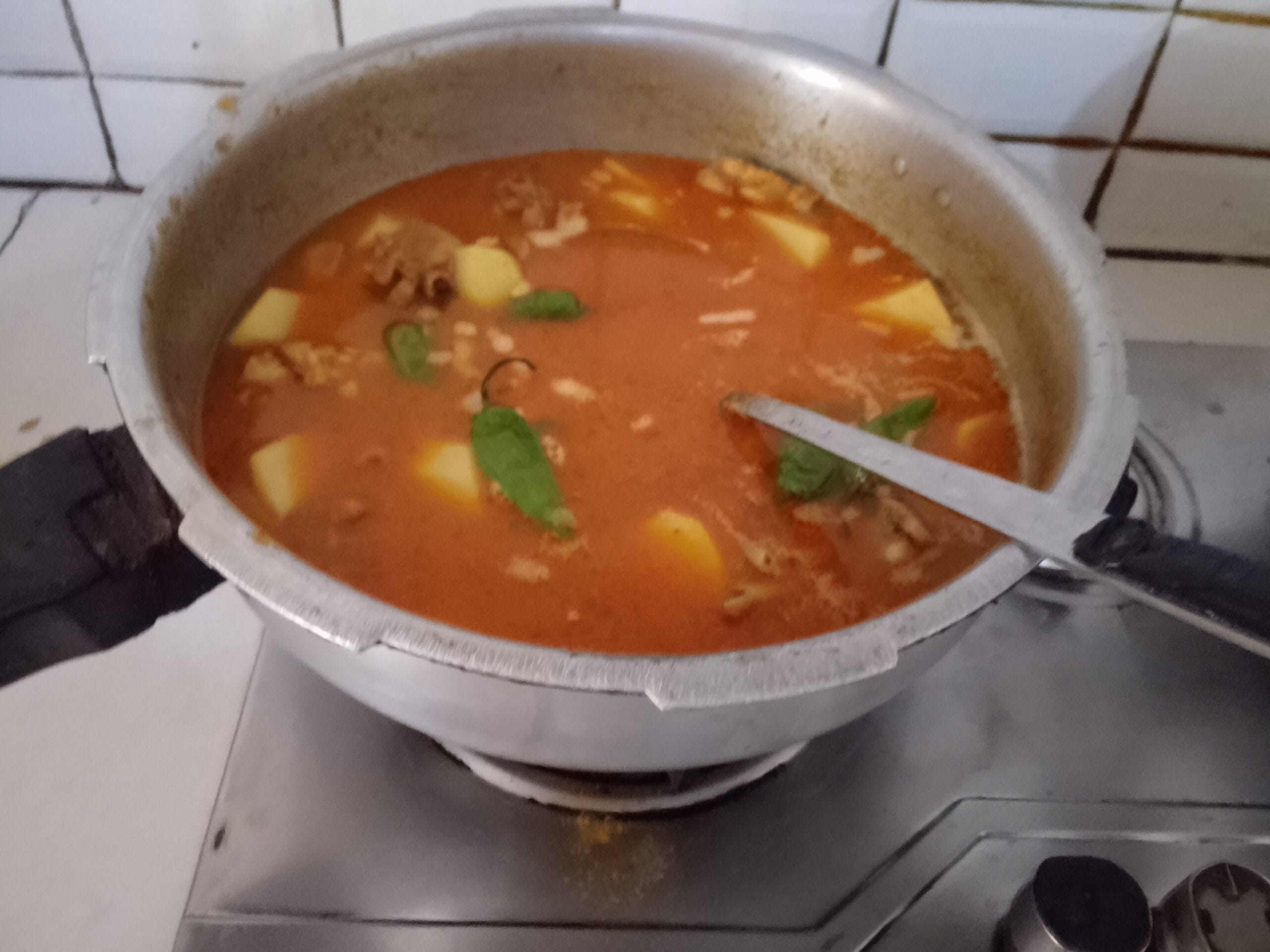 Simmering the rich gravy for the Aloo Chicken Recipe until tender.