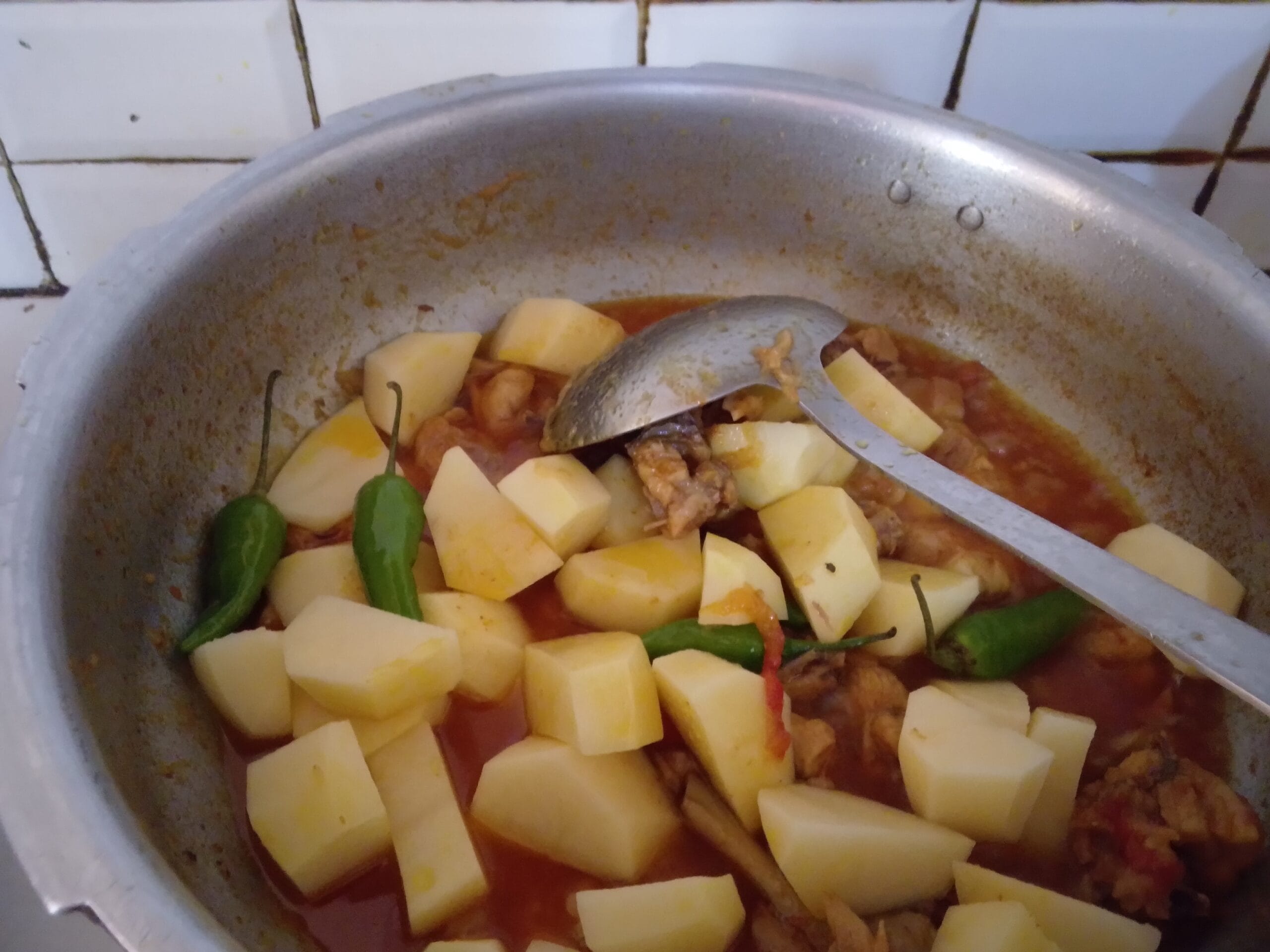 Frying potato pieces with chicken masala in the pan for the Aloo Chicken Recipe.