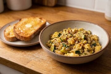 Scrambled eggs with zucchini garnished with red chili flakes and served warm with toast for Quick & Easy Zucchini Recipes
